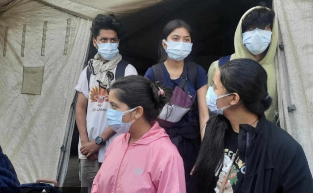 Three girls and two boys standing, wearing a mask