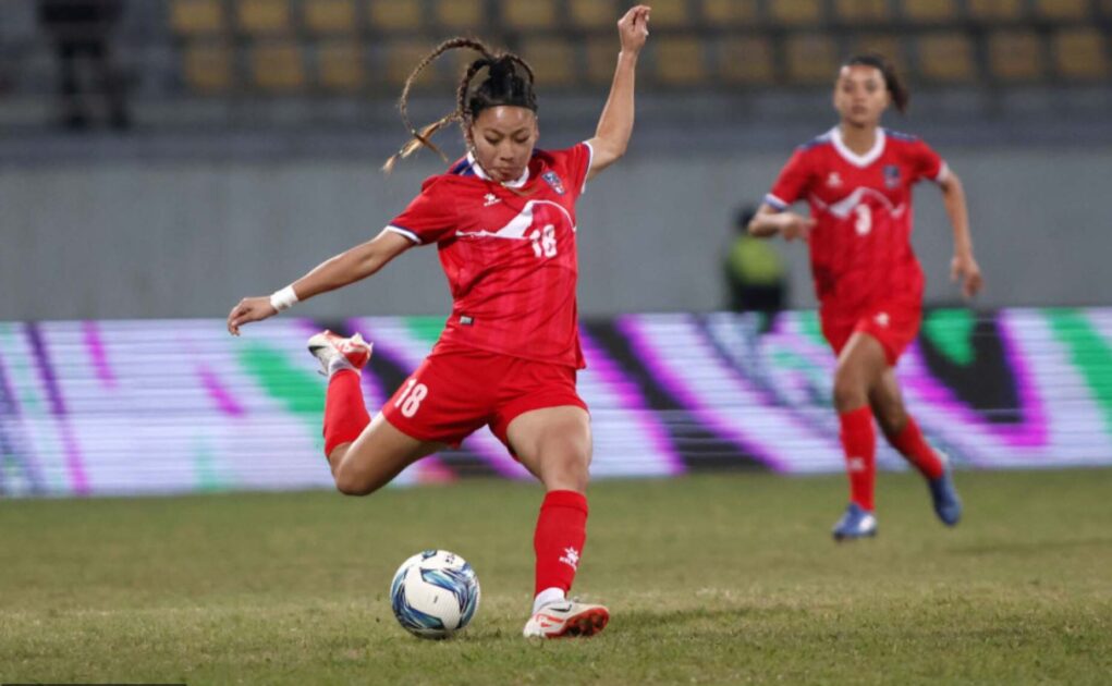 Two girls from myanmar women's football team trying to hit the goal
